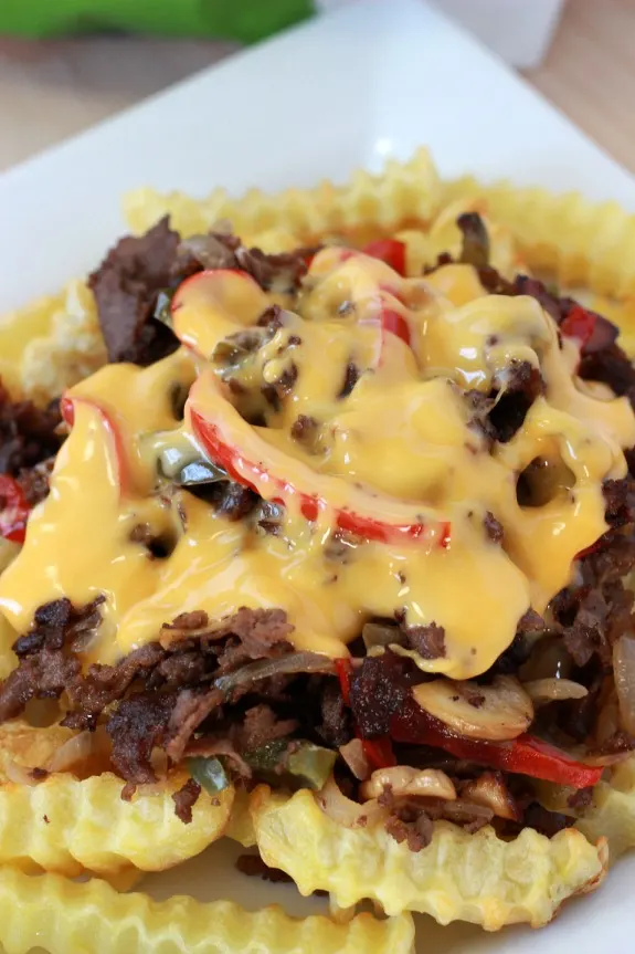 Philly Cheesesteak Fries. Baked french fries topped off with steak, onions, peppers, mushrooms and melted cheddar cheese sauce for the perfect game time grub.